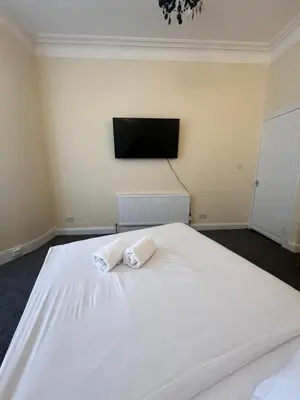 a large white bed with two white towels on it at Glasgow South 2 Bedroom Apartment in Glasgow