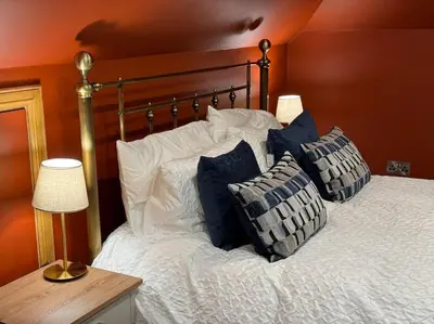 a bed with blue and white pillows on it at Stylish House with hot tub in Dalry