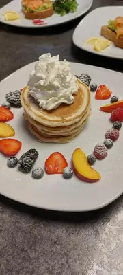 a white plate with pancakes and fruit on a table at St Ives Boutique Hotel in Dunoon