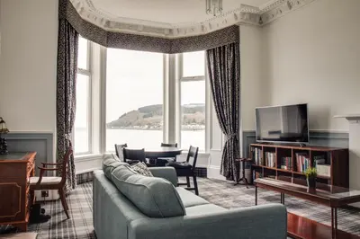 a living room with a couch and a large window at St Ives Boutique Hotel in Dunoon