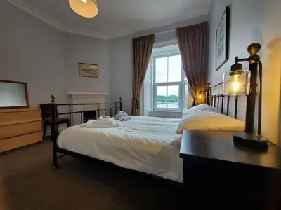 a bedroom with a large bed and a window at Little Bay View in Oban