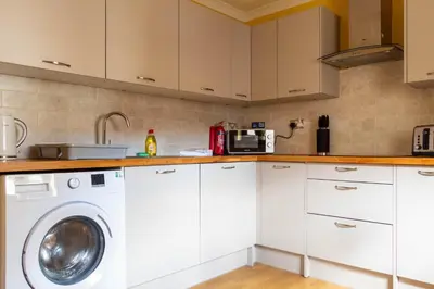 a kitchen with white cabinets and a washing machine at The Hill in Tillicoultry
