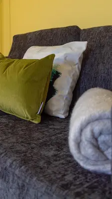 a couch with two pillows and a blanket on it at The Hill in Tillicoultry