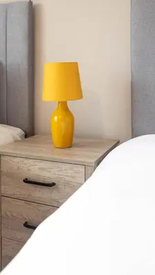 a yellow lamp sitting on a bedside table at Beth House in Bathgate