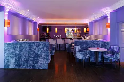 a dining room with purple walls and tables and chairs at Forrester Park Resort in Dunfermline
