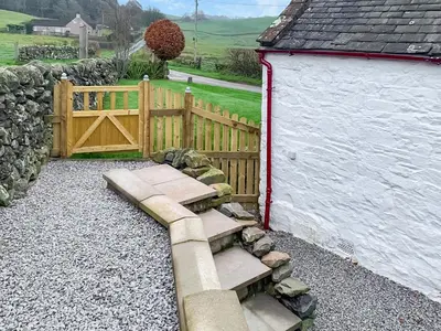 a wooden fence and stairs next to a building at Kilquhanity Cottage in Castle Douglas
