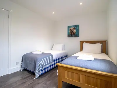 two beds in a room with white walls and wood floors at Renfrew Town Centre Easy Link to Glasgow City - Pass the Keys in Renfrew