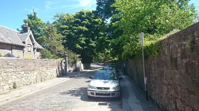 a row of cars parked next to a wall at Violet Bank Apartment Morningside in Edinburgh