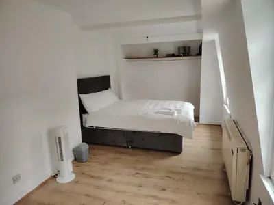 a small bedroom with a bed and a wooden floor at Bright Edinburgh Flat - City Center EB7 in Edinburgh