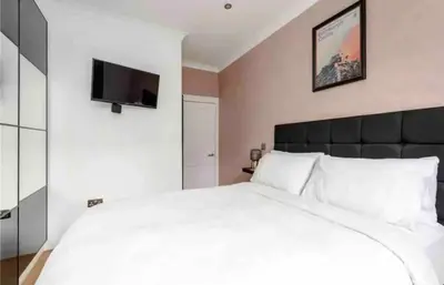 a bedroom with a white bed and a flat screen tv at amazing apartments - Avondale Pl by Stockbridge in Edinburgh