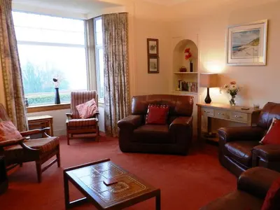 a living room with leather furniture and a large window at Goatfell View in Brodick