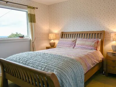 a bedroom with a large bed and a window at The Willows in Brodick