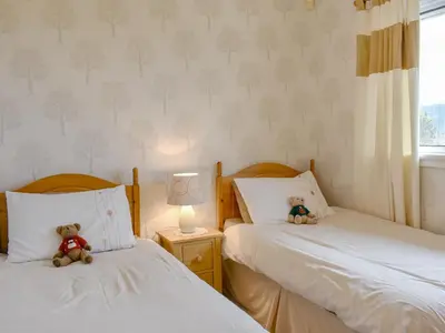 two teddy bears sitting on two beds in a bedroom at The Willows in Brodick