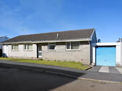 a white house with a blue garage at The Willows in Brodick