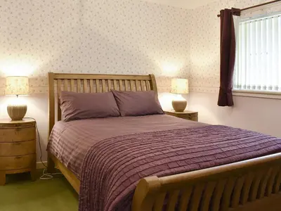 a bedroom with a bed with a purple bedspread and two lamps at The Willows in Brodick