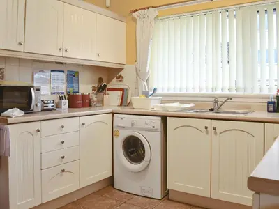a kitchen with a washing machine and a sink at The Willows in Brodick