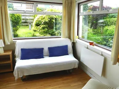 a white bench with two blue pillows in a room with windows at Hartholm in Brodick