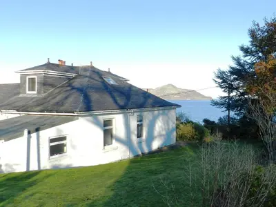 a white house sitting on top of a grass field at Ardbeag in Whiting Bay