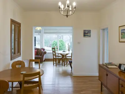 a dining room and living room with a table and chairs at Ardbeag in Whiting Bay
