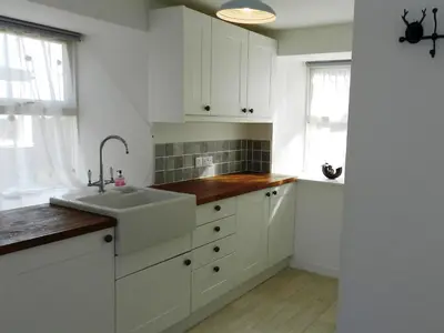 a kitchen with white cabinets and a sink at Craigard Cottage in Corrie