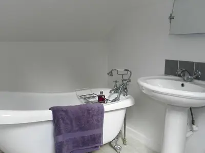 a bathroom with a sink and a bath tub next to a toilet and a sink at Craigard Cottage in Corrie