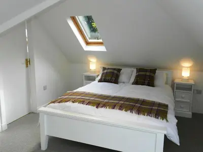 a white bed in a room with a window at Craigard Cottage in Corrie