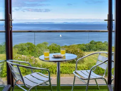 a table with two chairs and two glasses of orange juice at Woodlea Cottage 1 in Dippin