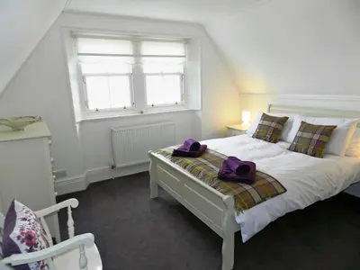 a bedroom with a bed with two purple bags on it at Craegard House in Corrie