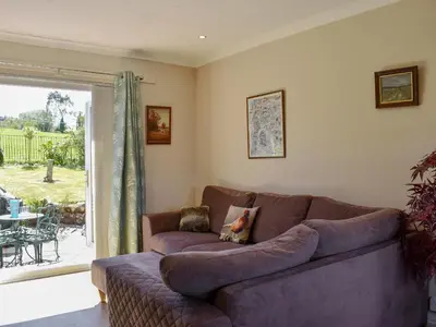 a living room with a brown couch and a sliding glass door at Fellview in Brodick