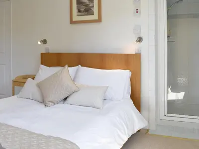 a bed with white sheets and pillows on it at Fellview in Brodick
