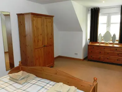 a bedroom with a wooden bed and a dresser at Glen Rosa Lodge in Brodick