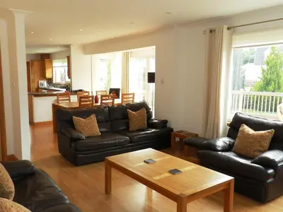 a living room with black leather furniture and a table at Glen Rosa Lodge in Brodick