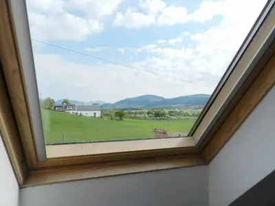 a window with a view of a green field at Torbeg Farm Cottage in Torbeg