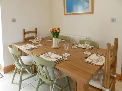 a dining room table with chairs and a wooden table with wine glasses at Torbeg Farm Cottage in Torbeg