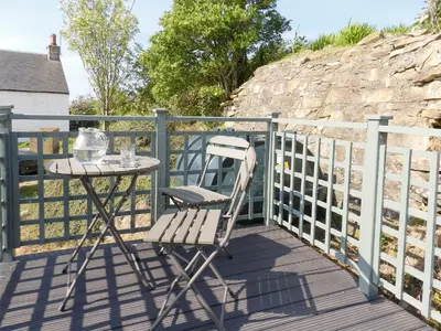 a table and a chair on a deck at Torbeg Farm Cottage in Torbeg