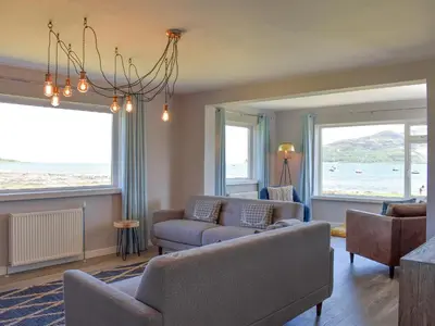 a living room with a couch and chairs and windows at Kinneil Land in Lamlash