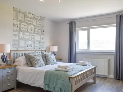 a bedroom with a large bed with a window at Kinneil Land in Lamlash