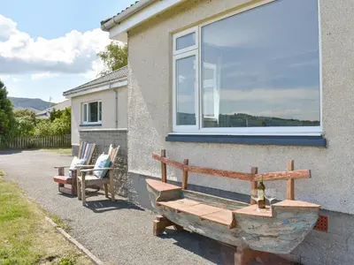 a bench outside of a house with a window at Kinneil Land in Lamlash