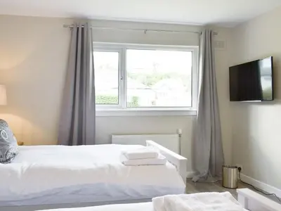a bedroom with a white bed and a window at Kinneil Land in Lamlash
