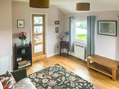 a living room with a couch and a table and a window at Hollinhaven in Blackwaterfoot