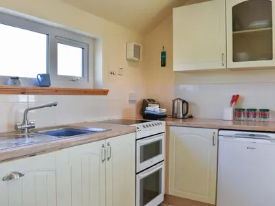 a kitchen with white cabinets and a sink at Hollinhaven in Blackwaterfoot