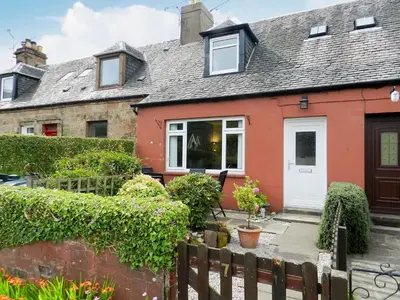 a red house with a white door at Sunnyside Cottage in Lamlash