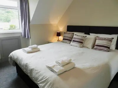 a bedroom with a large white bed with towels on it at Sunnyside Cottage in Lamlash