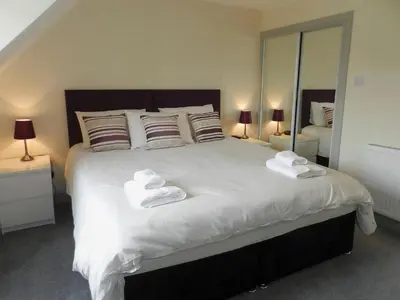 a bedroom with a large white bed with towels on it at Sunnyside Cottage in Lamlash