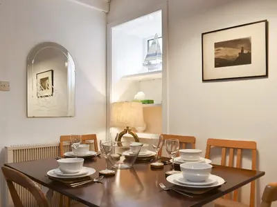 a dining room table with chairs and a wooden table with glasses at Ivy Cottage in Whiting Bay
