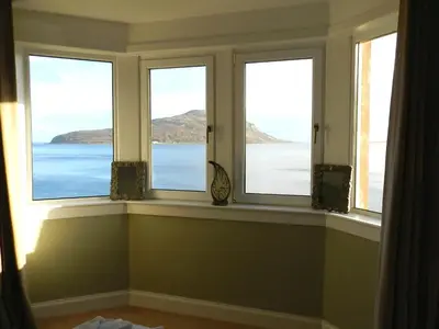 a room with three windows with a view of the ocean at St Brides in Lamlash