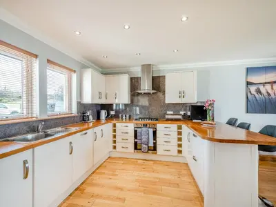 a kitchen with white cabinets and a wooden floor at Sky View in Ardmaleish