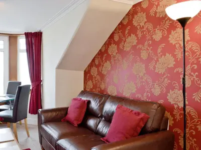 a brown leather couch in a living room with a wall at Apartment Sea View in Hunters Quay