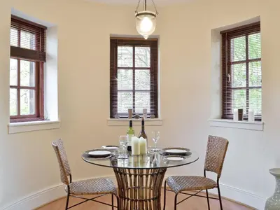 a dining room with a glass table and chairs at Brough Hall in Paisley