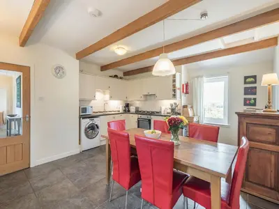 a kitchen with a wooden table and red chairs at Strathmaddie Farm Cottage in Palnure